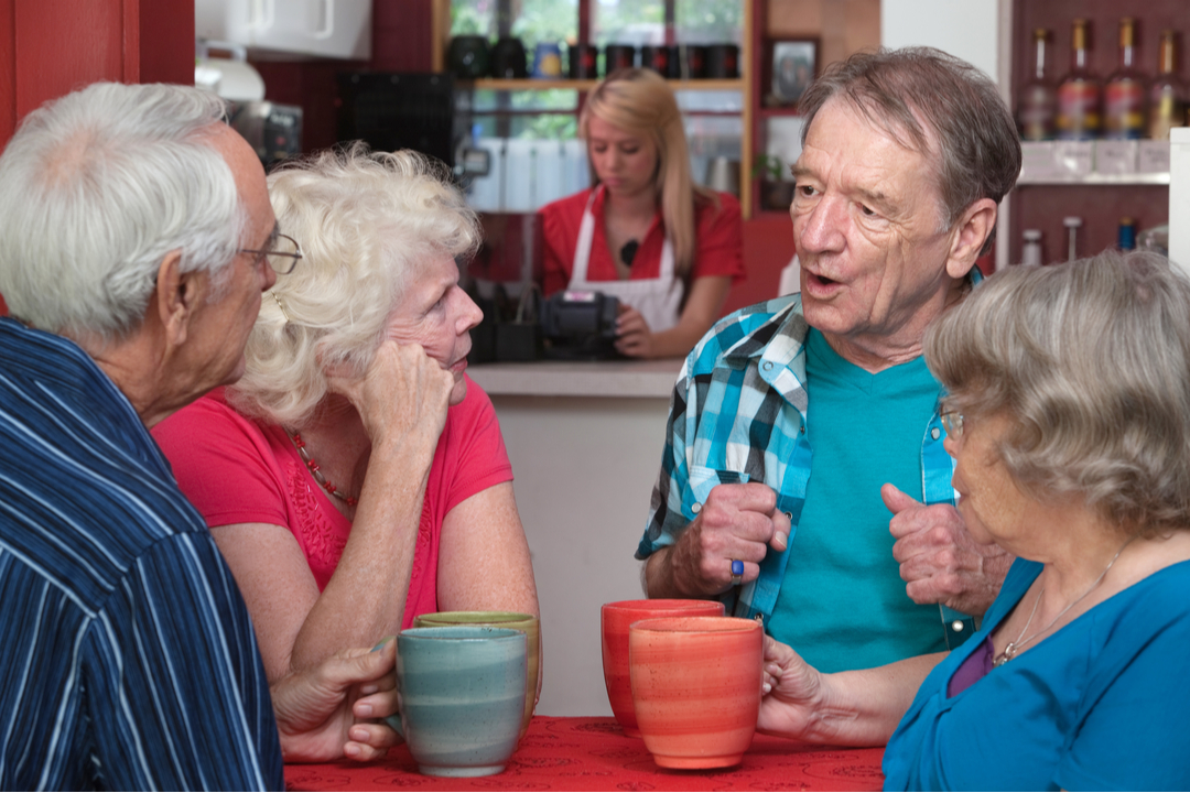 Four senior adults drinking coffee in a cafe